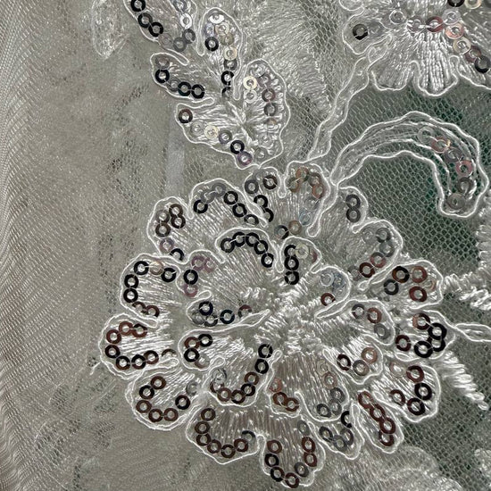 Luxury fancy lace fabric featuring delicate floral embroidery embellished with subtle sequins on a fine mesh base. 