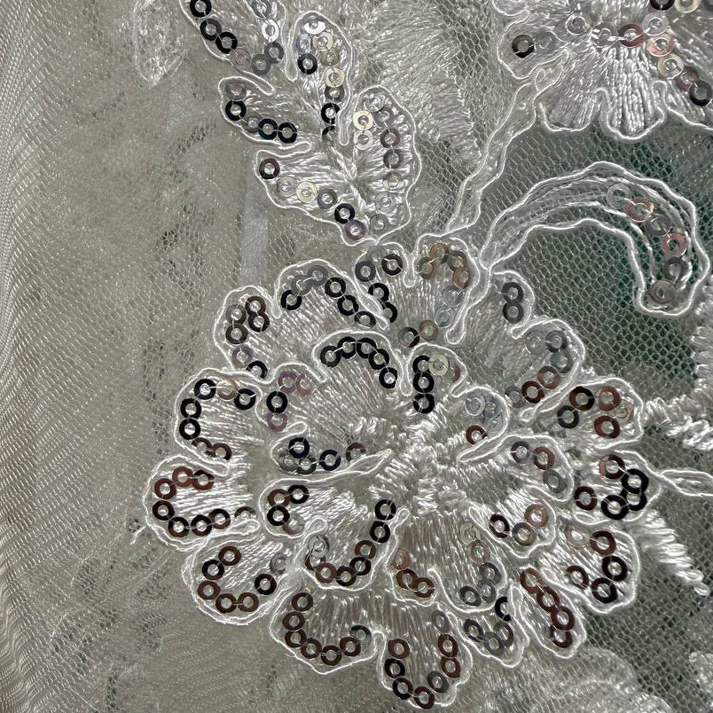 Luxury fancy lace fabric featuring delicate floral embroidery embellished with subtle sequins on a fine mesh base. 