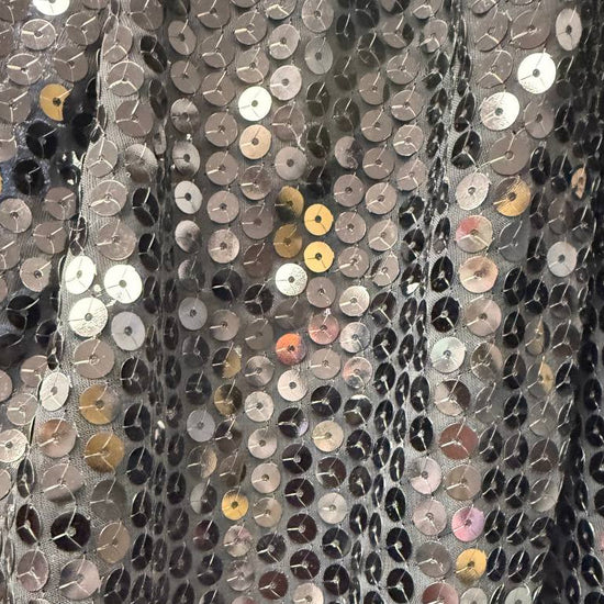 Black sequin fabric with dense round sequins sewn onto a soft mesh base, creating a bold reflective surface and fluid drape.