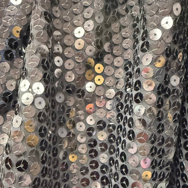Black sequin fabric with dense round sequins sewn onto a soft mesh base, creating a bold reflective surface and fluid drape.