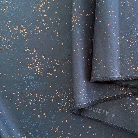 Ruby Star Society Speckled metallic cotton fabric available in navy, pink, and orange colors.