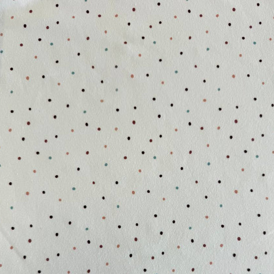 White cotton jersey knit fabric with small multicolor dot print and soft stretch texture.