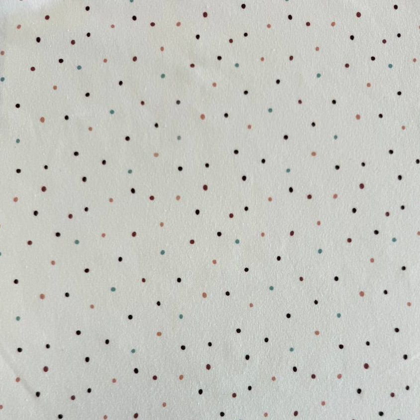 White cotton jersey knit fabric with small multicolor dot print and soft stretch texture.