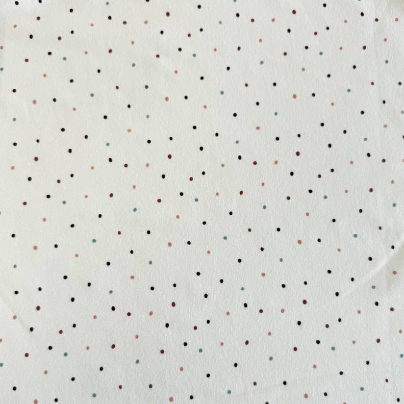 White cotton jersey knit fabric with small multicolor dot print and soft stretch texture.
