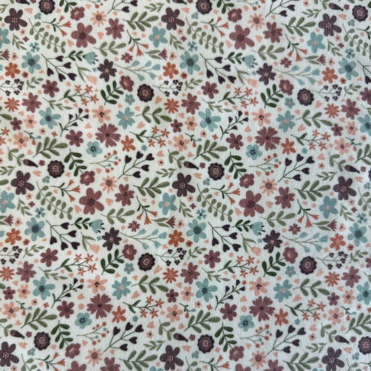 Noote floral cotton jersey fabric with dusty pink, mauve, sage, and blue flowers on an ivory background.
