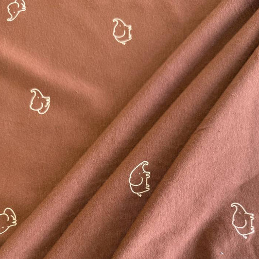 Brown cotton jersey knit fabric with small white elephant print.