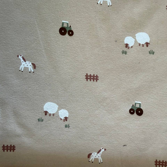 Beige cotton jersey fabric with small farm animals, sheep, horses, tractors, and fence illustrations.
