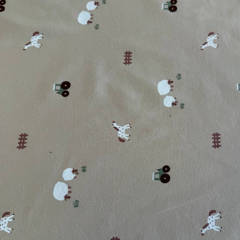 Beige cotton jersey fabric with small farm animals, sheep, horses, tractors, and fence illustrations.