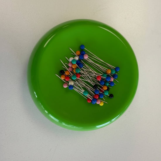 Grabbit magnetic pincushion available in red, black, and green colors with sewing pins attached to the magnetic surface.