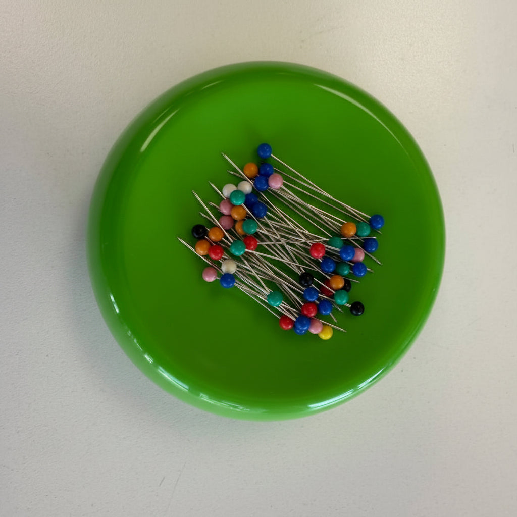 Grabbit magnetic pincushion available in red, black, and green colors with sewing pins attached to the magnetic surface.