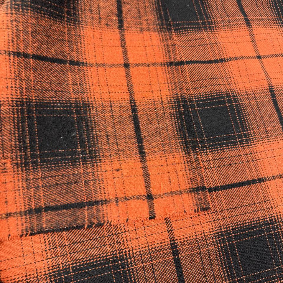 Orange and black yarn-dyed plaid fabric with a classic tartan-inspired pattern.
