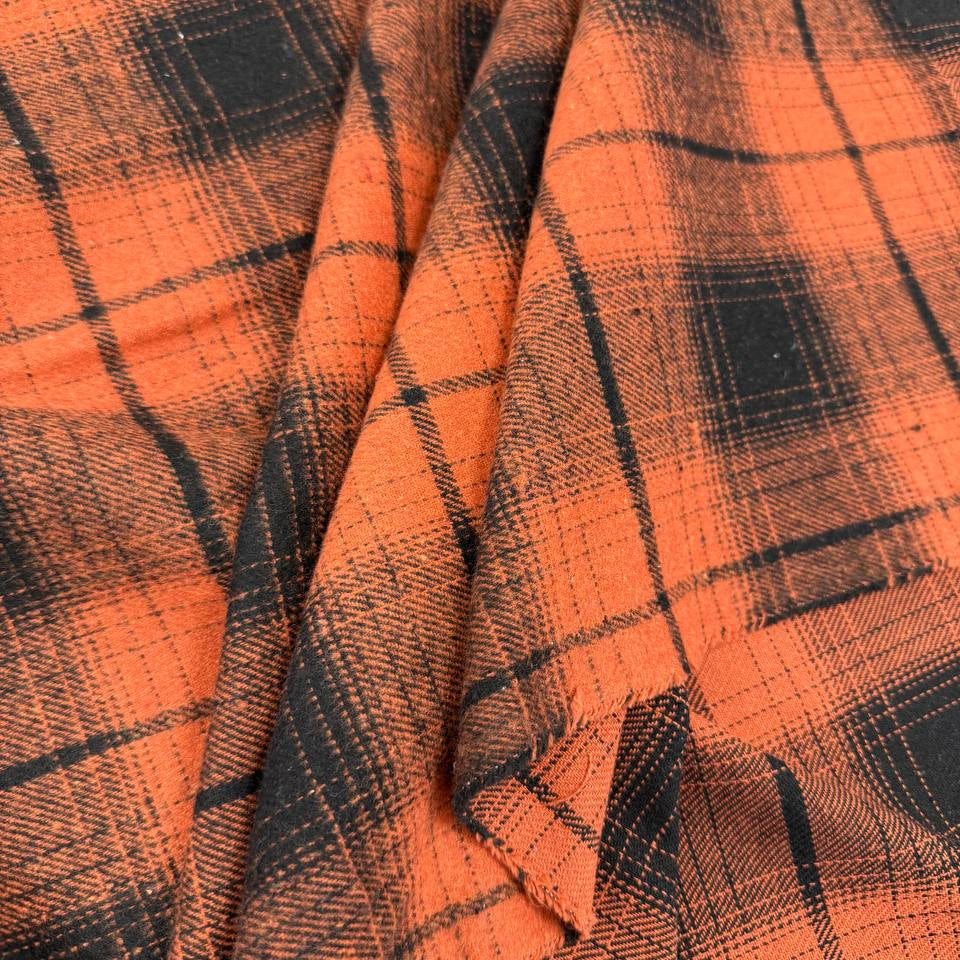 Orange and black yarn-dyed plaid fabric with a classic tartan-inspired pattern.