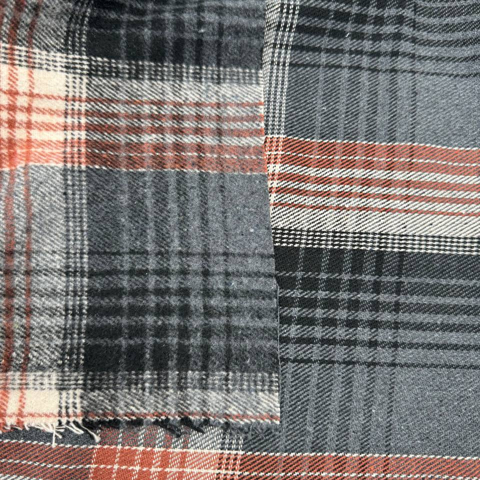 Black, grey, cream and rust double-sided plaid fabric with a classic yarn-dyed tartan pattern.