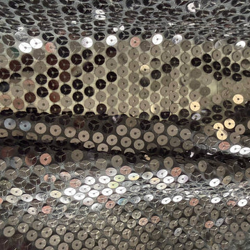Black sequin fabric with dense round sequins sewn onto a soft mesh base, creating a bold reflective surface and fluid drape.