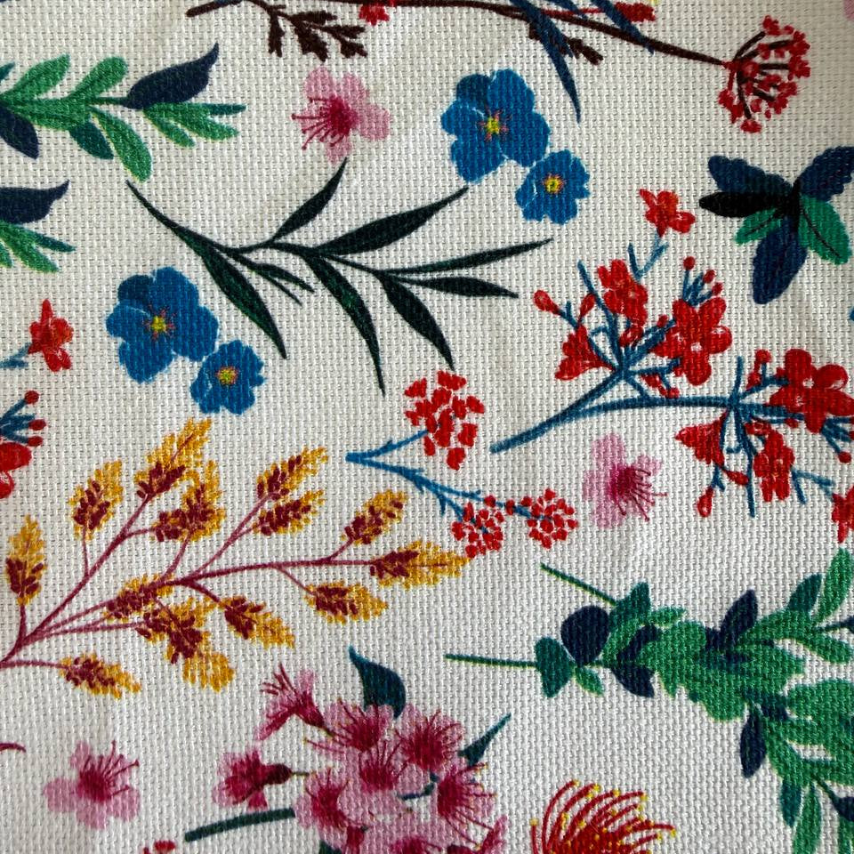 This cotton fabric features a delicate floral and botanical print on a light background.