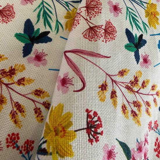 This cotton fabric features a delicate floral and botanical print on a light background.