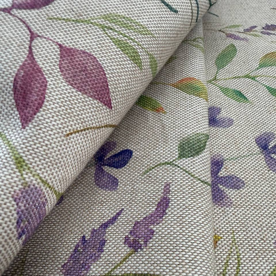 Decorative home décor fabric featuring a soft floral print in purple and green tones on a natural base.