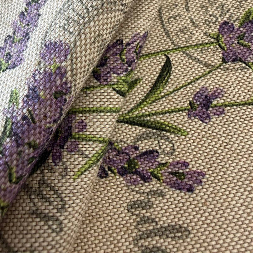 Elegant home décor fabric featuring a delicate lavender botanical print on a natural textured base.