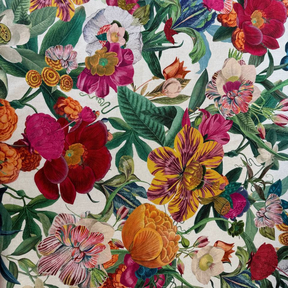 Beautiful botanical home décor fabric featuring an abundant floral garden print with vibrant flowers and lush green foliage on a soft ivory background