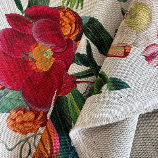 Beautiful botanical home décor fabric featuring an abundant floral garden print with vibrant flowers and lush green foliage on a soft ivory background