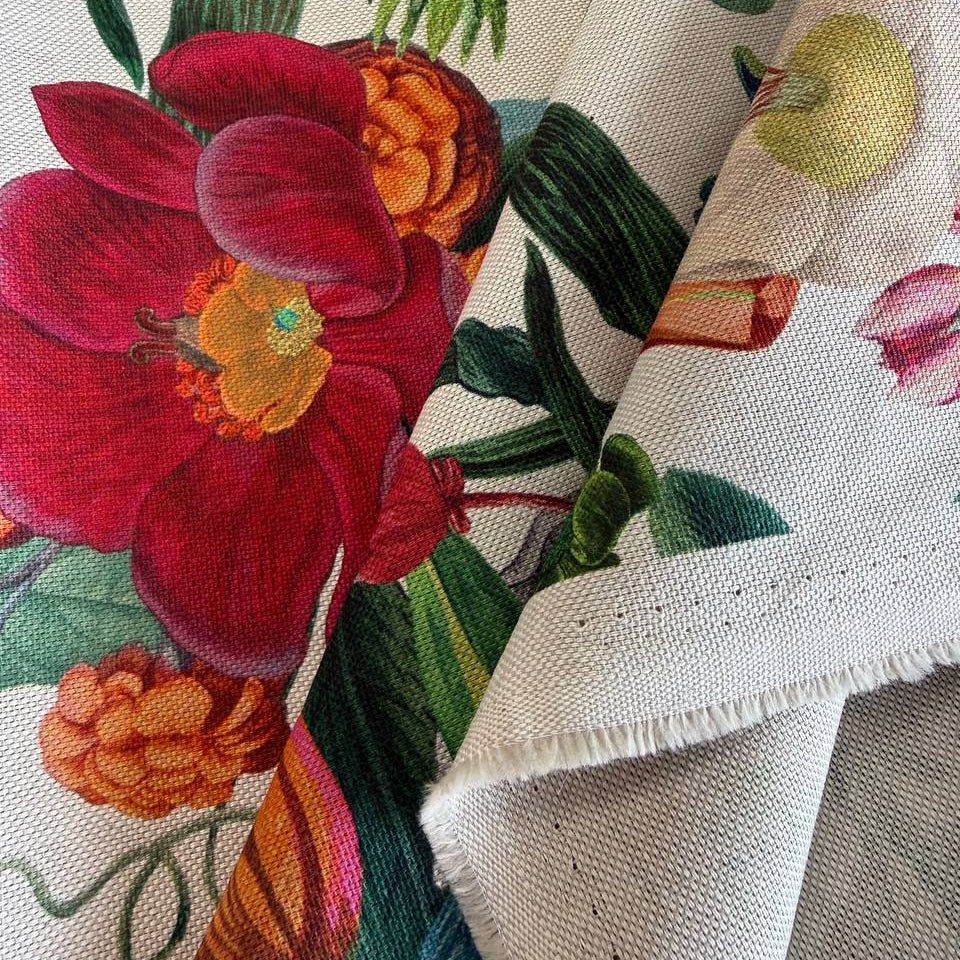 Beautiful botanical home décor fabric featuring an abundant floral garden print with vibrant flowers and lush green foliage on a soft ivory background