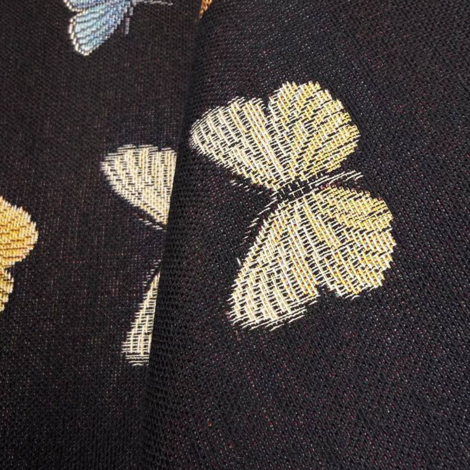 Decorative tapestry home décor fabric featuring colorful butterflies scattered across a deep black background