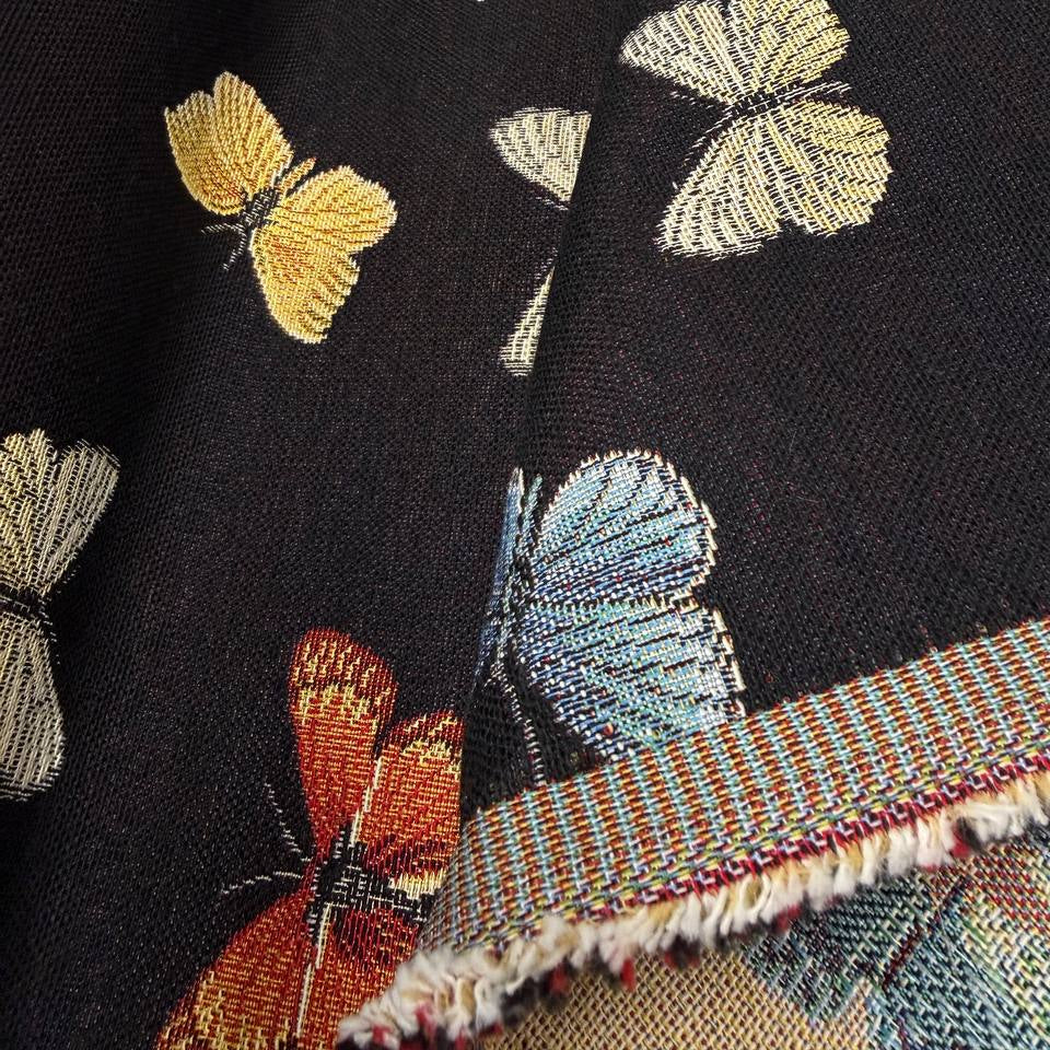 Decorative tapestry home décor fabric featuring colorful butterflies scattered across a deep black background
