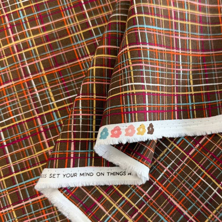 Brown quilting cotton featuring an intricate woven line plaid design in cocoa, orange, pink, blue, gold, and cream from the Things Above collection by Moda Fabrics.