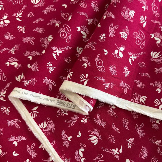 Crimson quilting cotton fabric featuring scattered cream and pink floral motifs from the Things Above collection by Stephanie Sliwinski for Moda Fabrics.