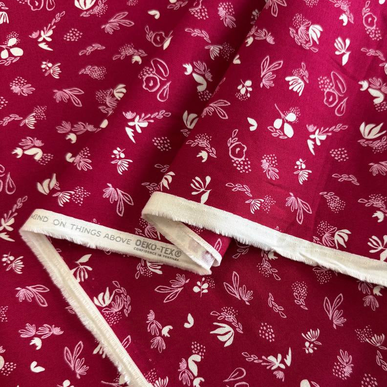 Crimson quilting cotton fabric featuring scattered cream and pink floral motifs from the Things Above collection by Stephanie Sliwinski for Moda Fabrics.