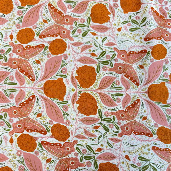 Woodland Wonder quilting cotton featuring pink butterflies, orange roses, soft pink leaves, and botanical motifs on a light cream background.