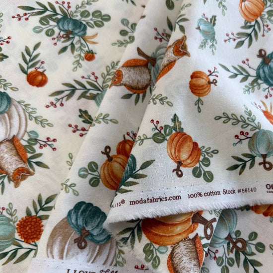 Autumn-themed quilting cotton featuring watercolor pumpkins, woodland elements, green foliage, and harvest florals on a light cream background from the I Love Fall Most Of All collection by Deb Strain for Moda Fabrics.