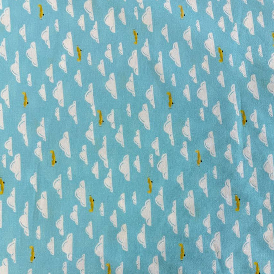 Light sky-blue quilting cotton featuring white clouds and small golden airplanes from the Aviation Adventures collection by Michael Miller.