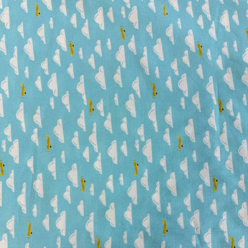Light sky-blue quilting cotton featuring white clouds and small golden airplanes from the Aviation Adventures collection by Michael Miller.