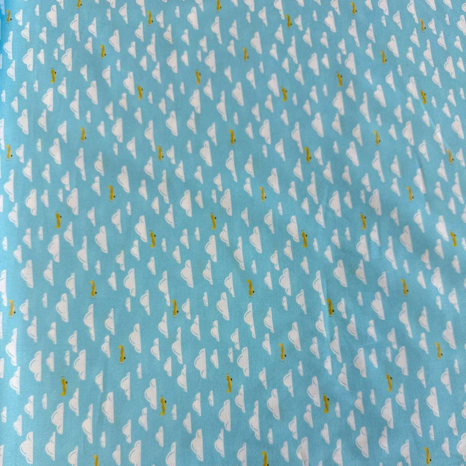 Light sky-blue quilting cotton featuring white clouds and small golden airplanes from the Aviation Adventures collection by Michael Miller.
