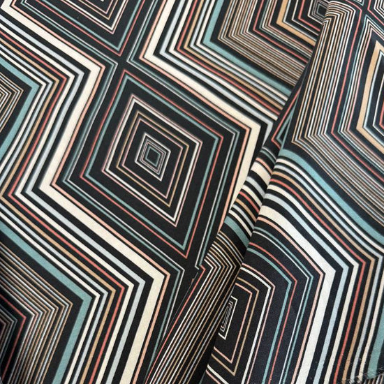 Nightlife geometric quilting fabric by Studio M for Moda Fabrics featuring layered diamond patterns in black, teal, cream, blush, coral, and gold tones.
