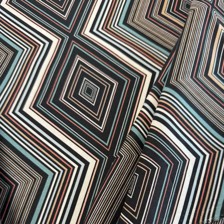 Nightlife geometric quilting fabric by Studio M for Moda Fabrics featuring layered diamond patterns in black, teal, cream, blush, coral, and gold tones.