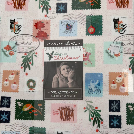 Tiny Christmas Layer Cake quilting fabric bundle by Moda Fabrics with Christmas postage stamp prints on cream background