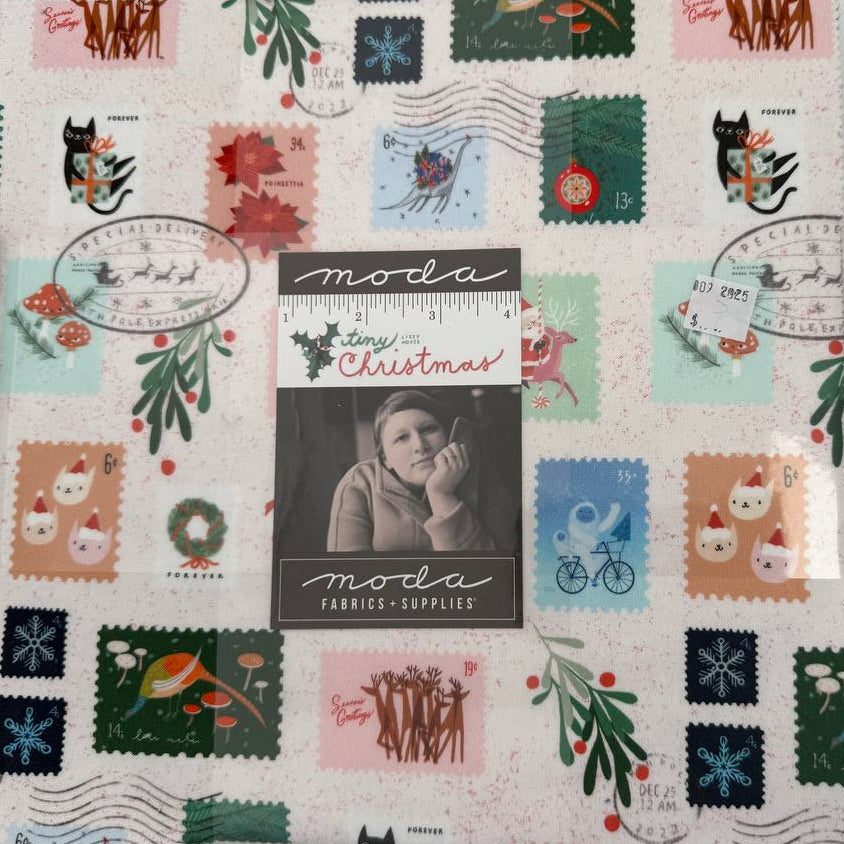 Tiny Christmas Layer Cake quilting fabric bundle by Moda Fabrics with Christmas postage stamp prints on cream background