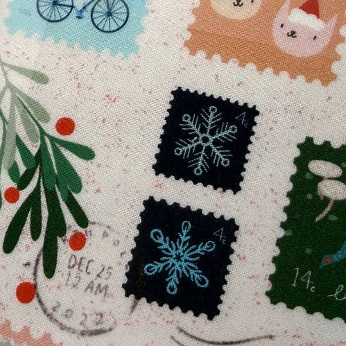 Tiny Christmas Layer Cake quilting fabric bundle by Moda Fabrics with Christmas postage stamp prints on cream background