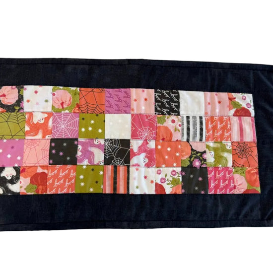 Mini Charm Hey Boo Table Runner Kit including Halloween-themed mini charm pack, coordinating black and pink fabrics, and batting for a festive quilted table runner.