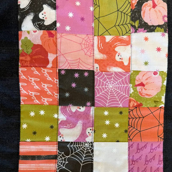 Mini Charm Hey Boo Table Runner Kit including Halloween-themed mini charm pack, coordinating black and pink fabrics, and batting for a festive quilted table runner.