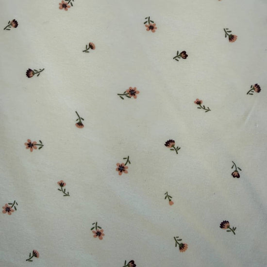 Floral cotton jersey knit fabric with small pink flowers on cream background