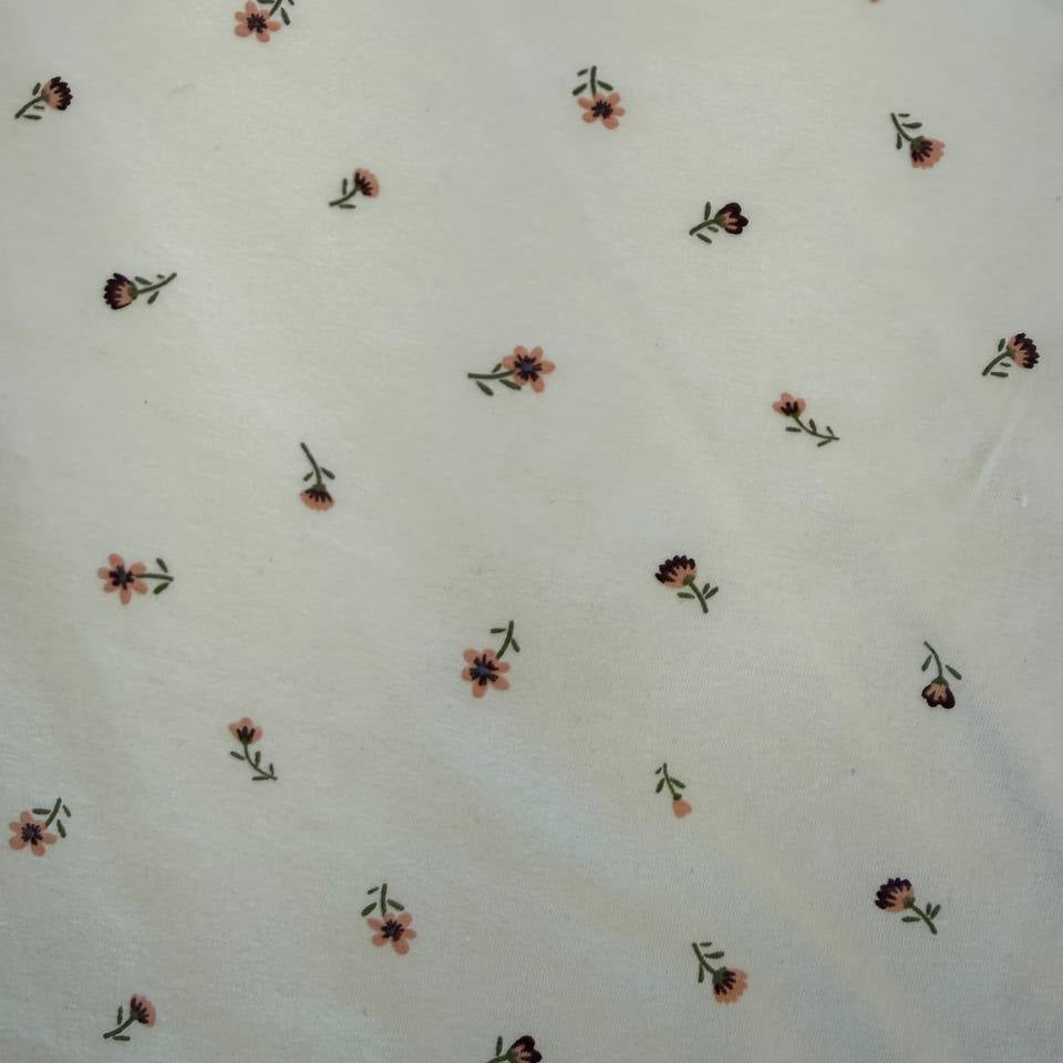 Floral cotton jersey knit fabric with small pink flowers on cream background