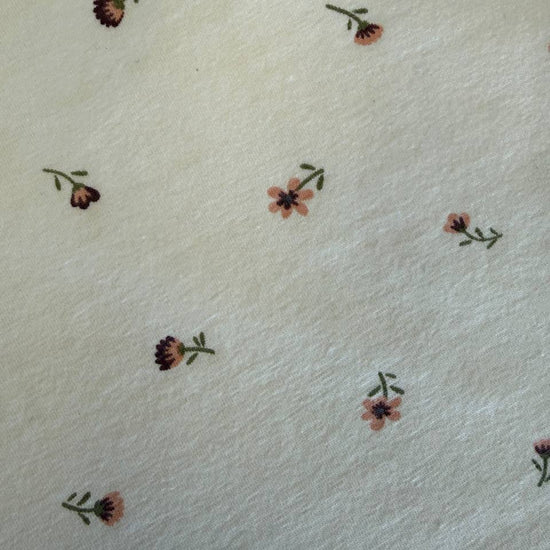 Floral cotton jersey knit fabric with small pink flowers on cream background
