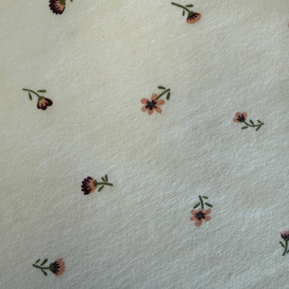 Floral cotton jersey knit fabric with small pink flowers on cream background