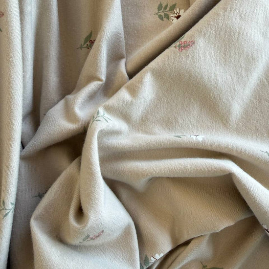 Beige cotton jersey fabric with small scattered floral print