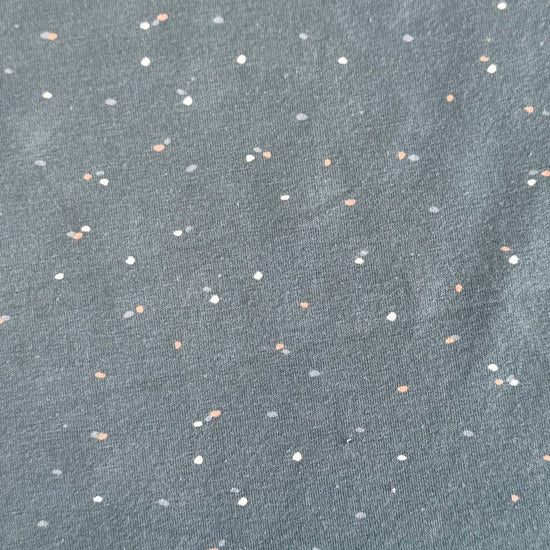 Dusty blue cotton jersey fabric with multicolor speckles, soft stretch knit textile close-up