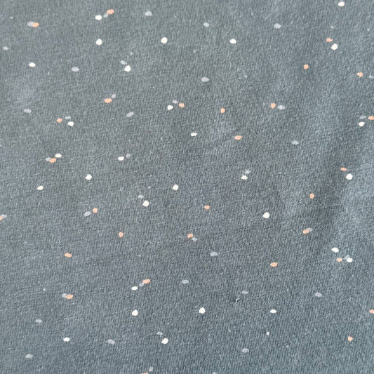 Dusty blue cotton jersey fabric with multicolor speckles, soft stretch knit textile close-up