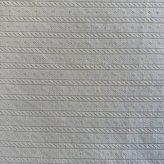 Soft cream cotton pointelle knit fabric with delicate textured pattern